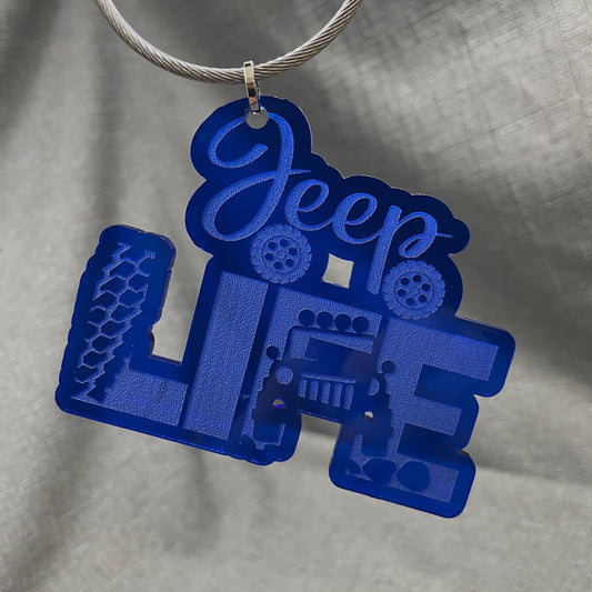 Blue Jeep car charm featuring the word JEEP with Jeep tires underneath, the word LIFE alongside tire tracks, and an off-roading Jeep driving toward the viewer.