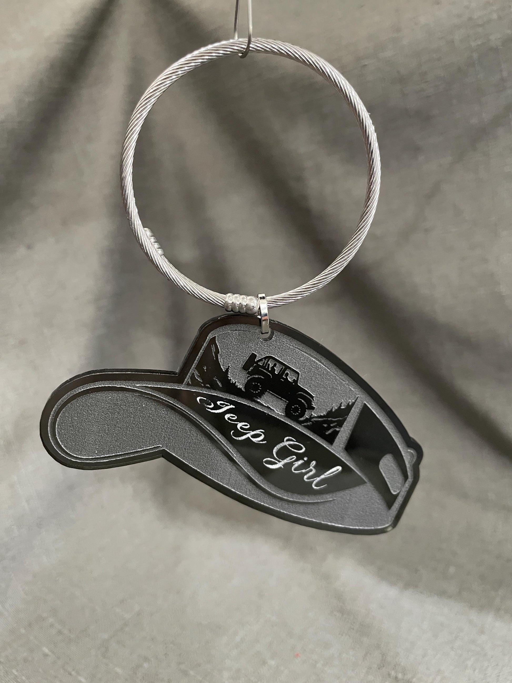 Smoke gray key charm hanging from a key loop, suspended in the air to emphasize its sleek look.