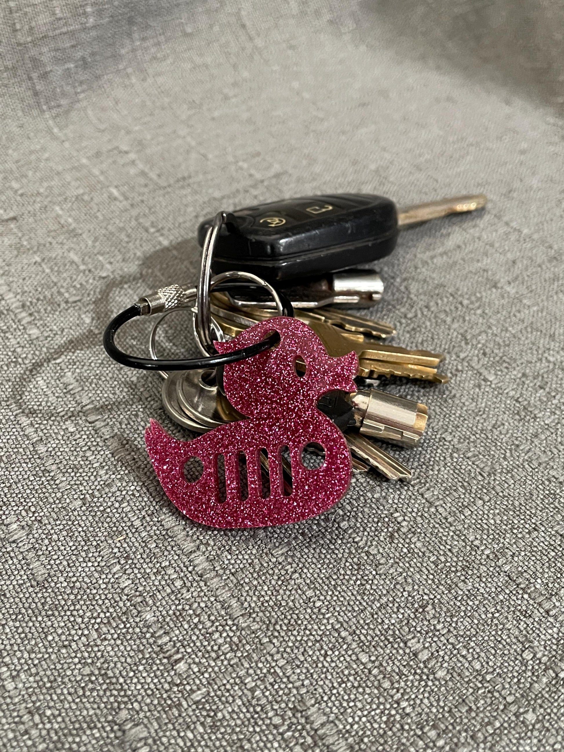 Glitter pink mini duck key chain with Jeep grill cut-out on a set of keys, adding a playful touch for Jeep enthusiasts.