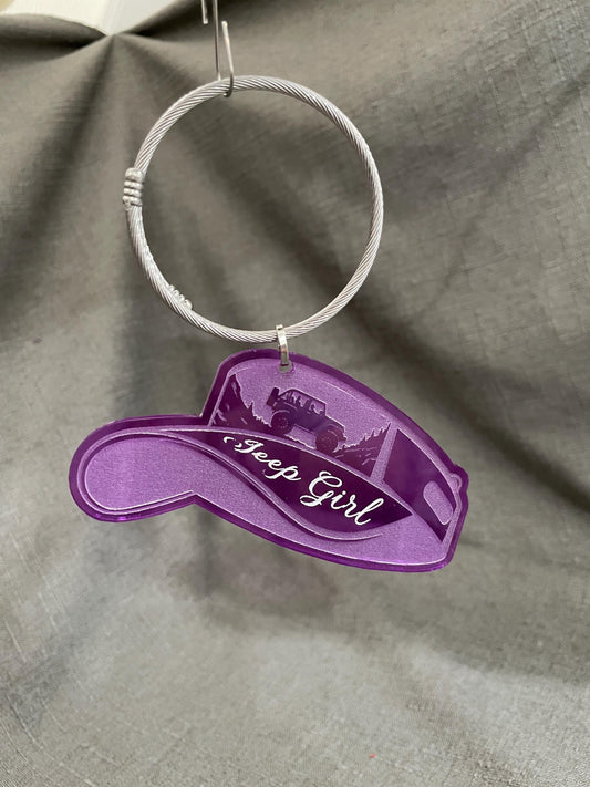 Purple key charm hanging from a key loop, suspended in the air to display its vibrant hue.